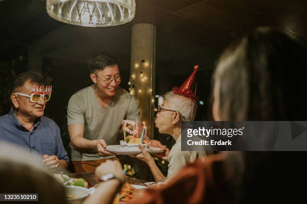wishing you luck, son gives birthday cake to his mother -stock photo - senior woman birthday stock pictures, royalty-free photos & images
