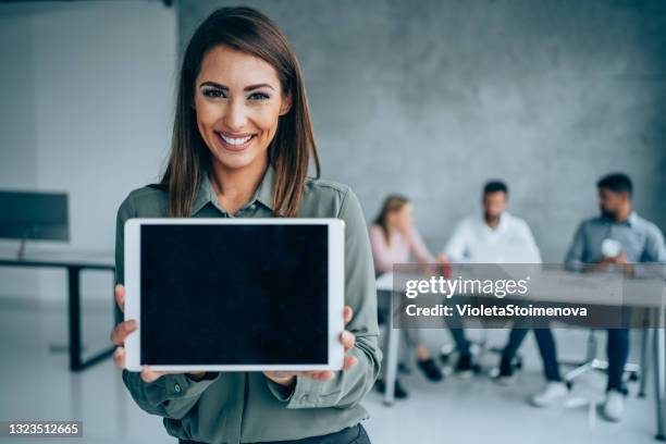 smiling businesswoman standing in front of her team and holding digital tablet with black blank screen. - showing ipad stock pictures, royalty-free photos & images