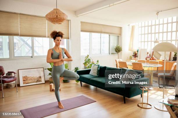 young woman practicing tree pose at home - tree position stock pictures, royalty-free photos & images