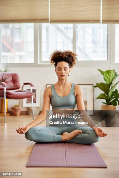 young woman practicing breathing exercise at home - yoga stock-fotos und bilder