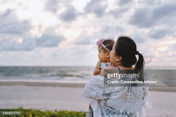 mother hugging her baby girl at beach - kota kinabalu beach stock pictures, royalty-free photos & images