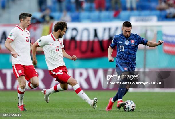 Robert Mak of Slovakia runs with the ball whilst under pressure from Robert Lewandowski and Bartosz Bereszynski of Poland during the UEFA Euro 2020...