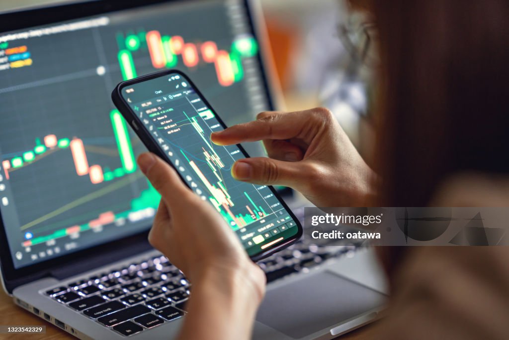 Woman is checking Bitcoin price chart on digital exchange on smartphone, cryptocurrency future price action prediction.