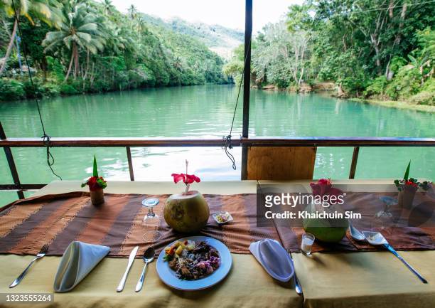 dining table facing river and rainforest, with red hibiscus flower decoration on a coconut - bohol philippines stock pictures, royalty-free photos & images