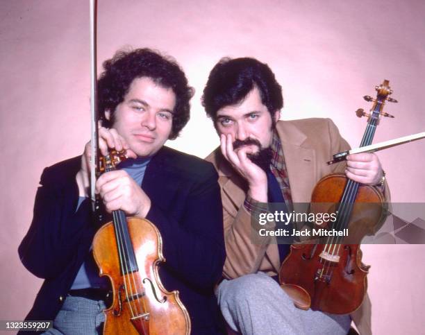 Portrait of classical musicians Pinchas Zukerman and Itzhak Perlman as they pose with their instruments, December 1979.