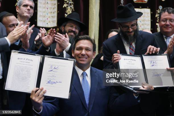 Florida Gov. Ron DeSantis holds up two bills he signed at the Shul of Bal Harbour on June 14, 2021 in Surfside, Florida. The bills are HB 529 and HB...