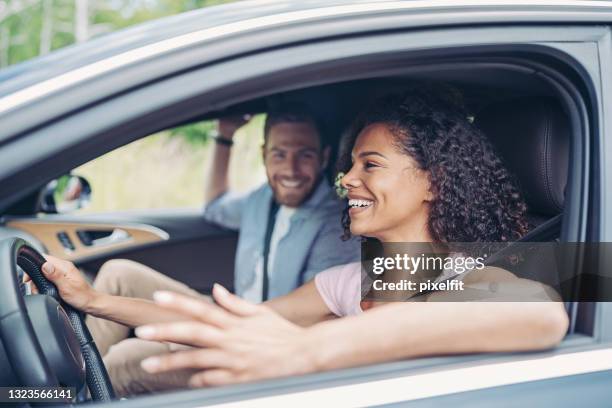 smiling young woman driving a car and talking with her boyfriend - couple in car smiling stock pictures, royalty-free photos & images