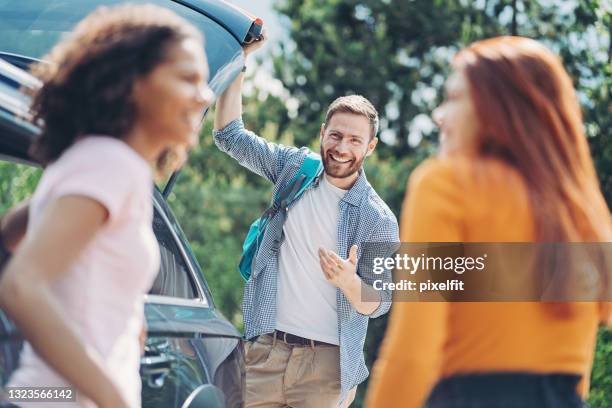 cheerful young man and two girls by a car - car sharing stock pictures, royalty-free photos & images