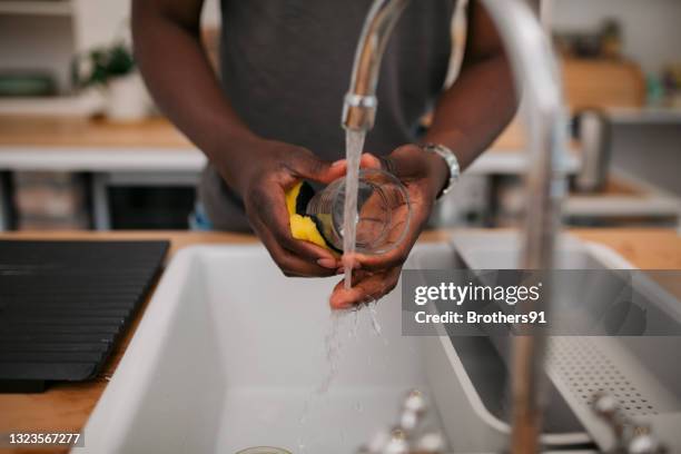 unrecognizable african american man washing dishes at home - dirty sink stock pictures, royalty-free photos & images