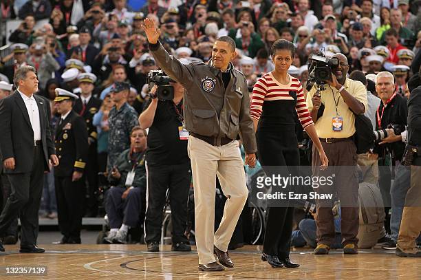 President Barack Obama and first lady Michelle Obama walk to the court and wave before the start of the NCAA men's college basketball Carrier Classic...