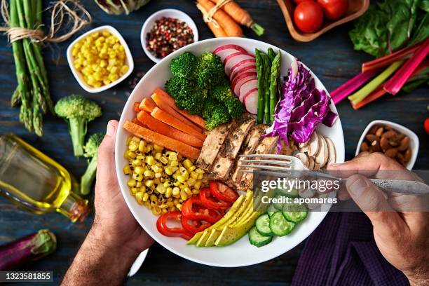 conceptos de alimentación y dieta saludables. vista superior de las manos del hombre sosteniendo una ensalada fresca saludable en un tazón con verduras crudas al fondo. - fibra fotografías e imágenes de stock