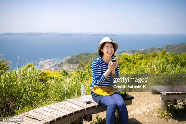 young woman eating 'onigiri' japanese rice ball at the mountain peak - rice ball stock pictures, royalty-free photos & images