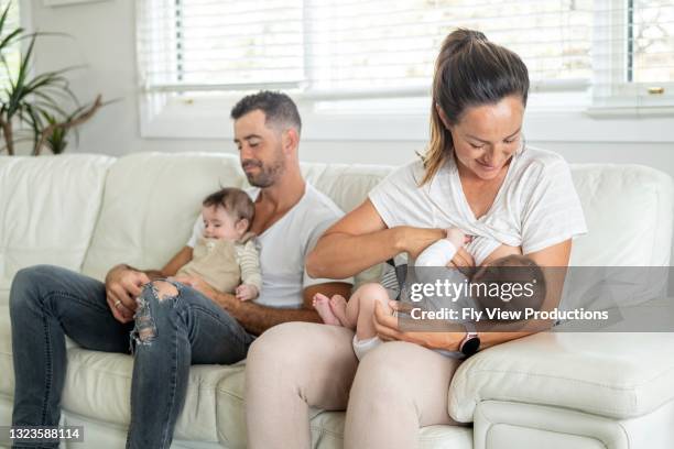 beautiful mother breastfeeds one of her twin boys - latch stock pictures, royalty-free photos & images