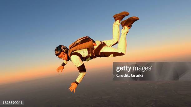 a parachutist in free fall at the sunset. - aerial stunts flying stock pictures, royalty-free photos & images