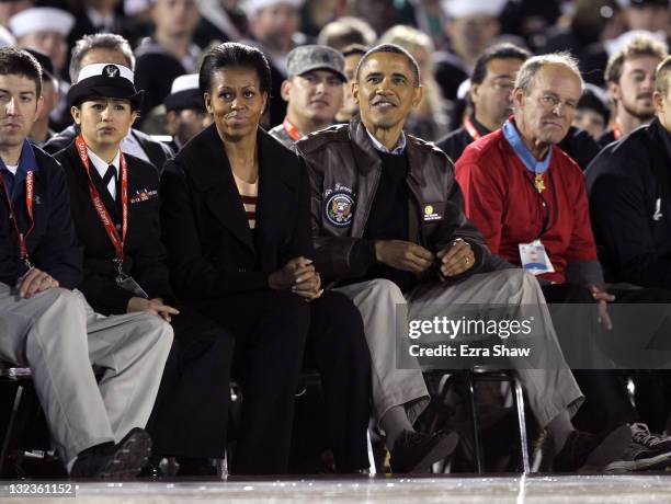 President Barack Obama and first lady Michelle Obama watch the NCAA men's college basketball Carrier Classic between the Michigan State Spartans and...