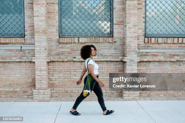 happy woman walking in the street - geht stock-fotos und bilder
