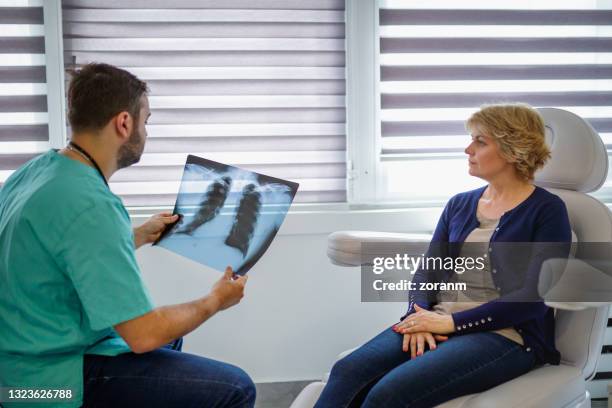 radiologist holding x-ray and reading results for female patient - emphysema stock pictures, royalty-free photos & images