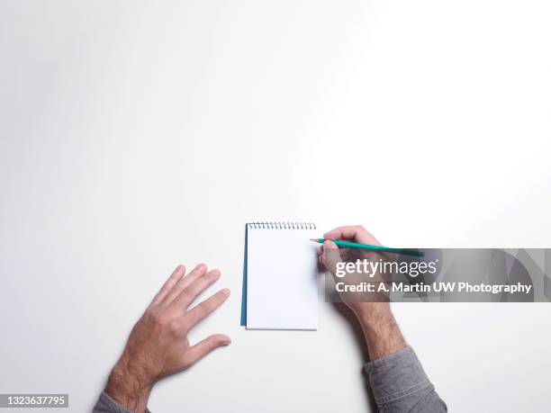 man hands writing on an empty notebook  on white table, flat lay style. planning concept - hand pen stock-fotos und bilder