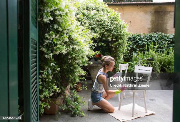 diy: woman painting wooden chairs in back yard - kunstnijverheid stockfoto's en -beelden