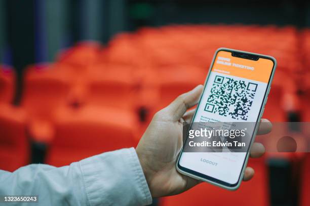 asian chinese man using mobile app cinema movie e-ticketing reservation looking for seat inside cinema hall - loket stockfoto's en -beelden