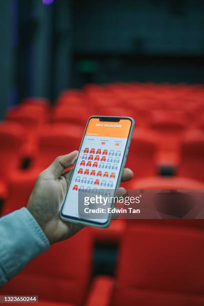 asiatische chinesische mann mit mobilen app kino film e-ticketing reservierung auf der suche nach sitz in kinosaal - ticket line concert stock-fotos und bilder