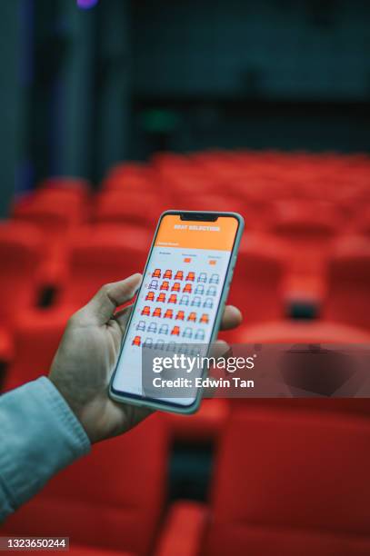 asian chinese man using mobile app cinema movie e-ticketing reservation looking for seat inside cinema hall - ticket line concert stock pictures, royalty-free photos & images