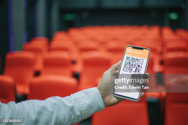 asiatico cinese uomo utilizzando mobile app cinema film prenotazione e-ticketing alla ricerca di posto all'interno sala cinema - biglietto foto e immagini stock