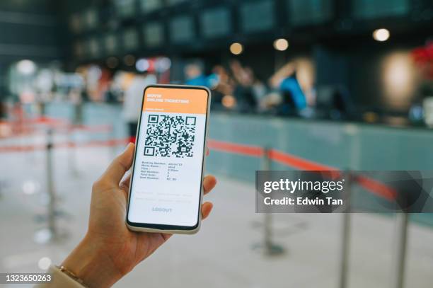 donna asiatica cinese utilizzando mobile app cinema film prenotazione e-ticketing di fronte al banco dei biglietti del cinema - biglietto foto e immagini stock
