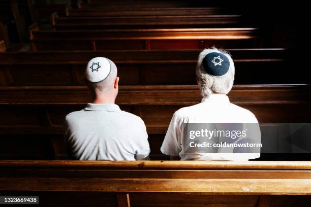 jüdische männer sitzen zusammen und beten in der synagoge - synagogue stock-fotos und bilder