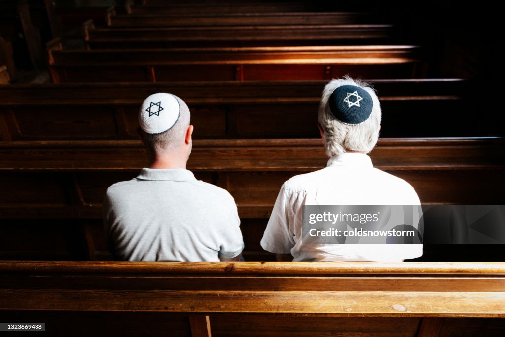 Jewish men sitting together and praying inside synagogue
