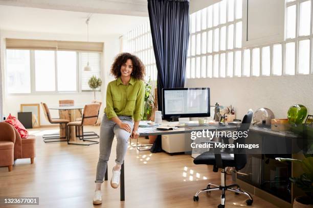 female freelancer sitting on desk at home office - at home portrait fotografías e imágenes de stock