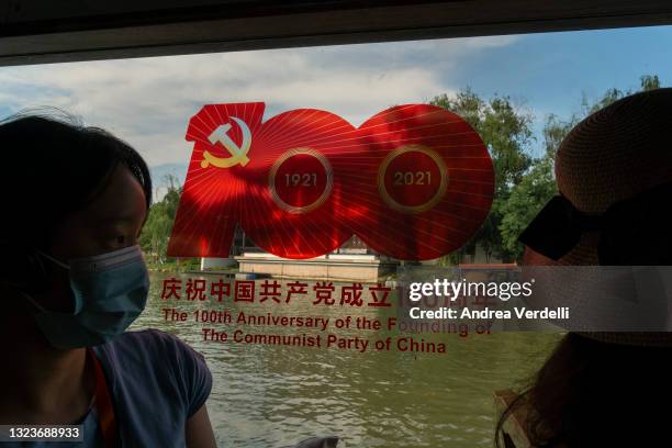 Local journalists sit on a boat with a sign commemorating the 100th anniversary of the founding of the Communist Party of China, stamped on the...