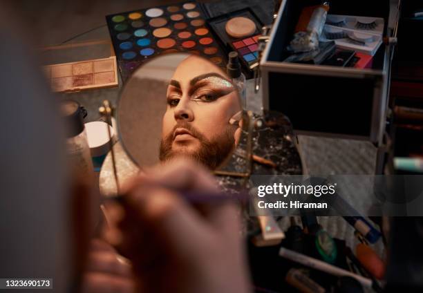 shot of a young man applying theatrical makeup to his face in a studio - make up mirror stock pictures, royalty-free photos & images
