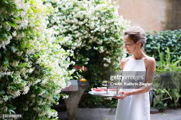 woman holding tray with champagne glasses and red shrimp, outdoors in back yard - hostess stock pictures, royalty-free photos & images