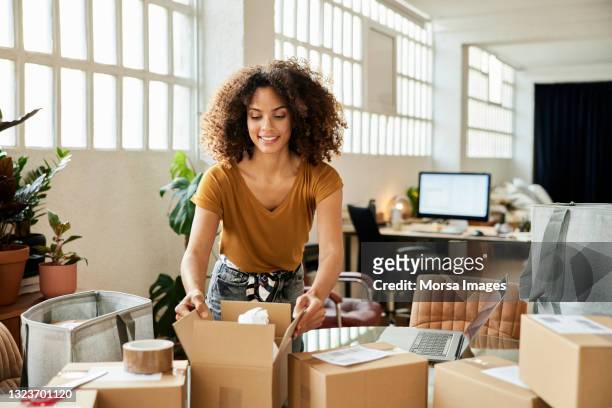 female entrepreneur packing boxes at home - women entrepreneur imagens e fotografias de stock