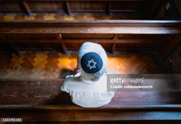 senior jewish man wearing skull cap praying inside synagogue - synagoga bildbanksfoton och bilder