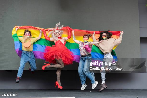 grupo de amigos de diferentes orientações sexuais celebram o orgulho gay usando sua bandeira do arco-íris e roupas multicoloridas enquanto olha para a câmera e os retratam segurando a bandeira gay - beautiful transvestite - fotografias e filmes do acervo