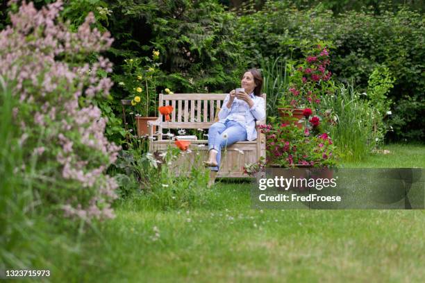jardinería - la mujer disfruta de relajarse en el jardín - banco asiento fotografías e imágenes de stock