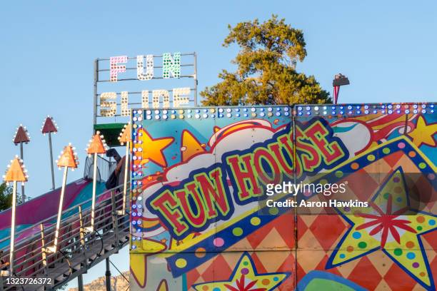 fun house and slide at a traveling carnival in a public park - fun house stock pictures, royalty-free photos & images