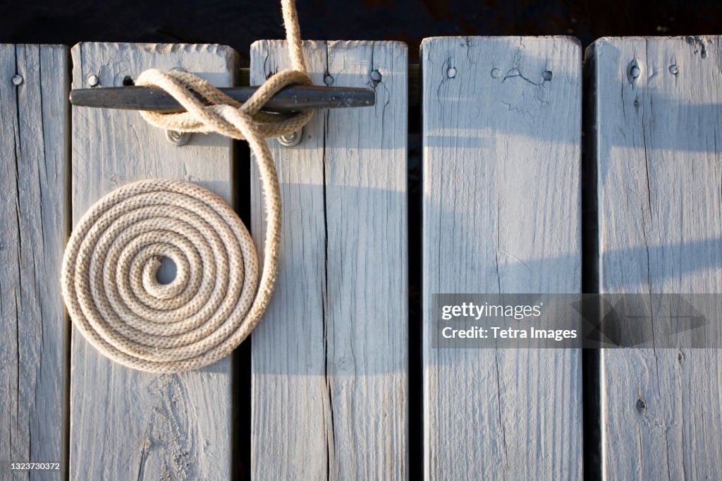 Overhead view of coiled rope tied around bollard