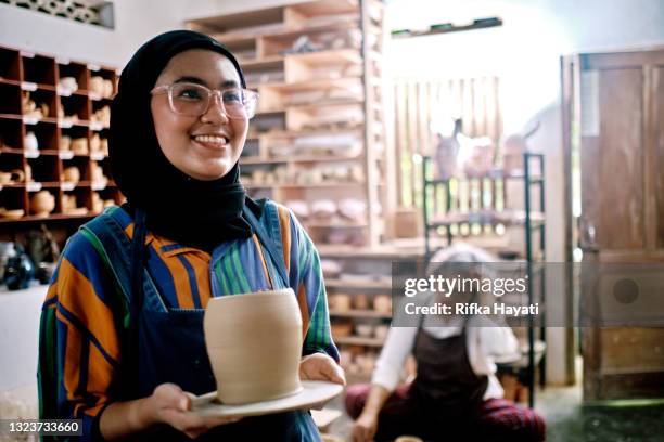 young hijab woman showing the pot she made during workshop - heritage round two imagens e fotografias de stock