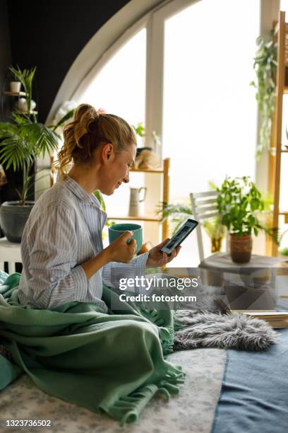 woman enjoying coffee in bed and reading news on smart phone - read and newspaper and bed stock pictures, royalty-free photos & images