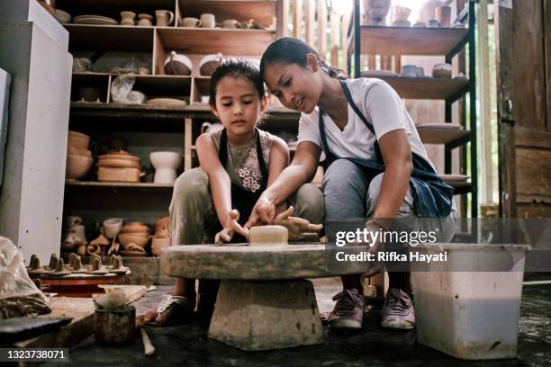 mother having fun potter teaching the art of pot making with her daughter - javanese handicrafts stock pictures, royalty-free photos & images