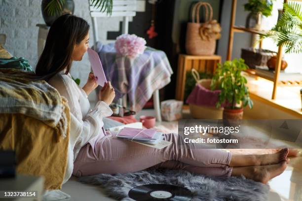 young woman contemplating reading a letter - receiving card stock pictures, royalty-free photos & images