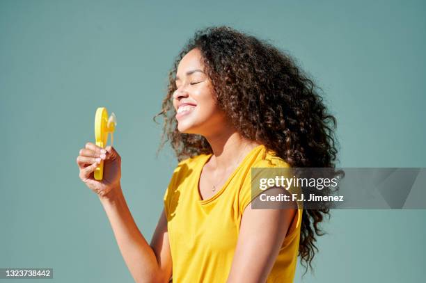 woman with portable fan on the street - african american women in the wind photos et images de collection