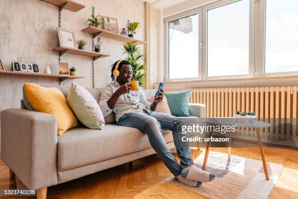 homem relaxando em casa com música, café e mídias sociais - contente - fotografias e filmes do acervo