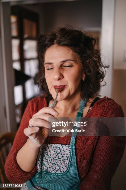 mujer lamiendo la cuchara con crema de chocolate - cuchara fotografías e imágenes de stock