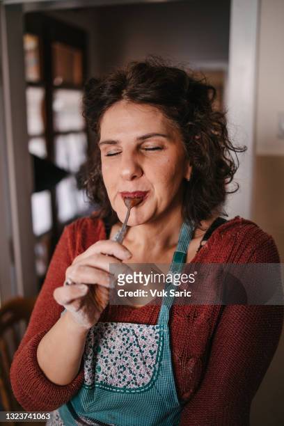 femme léchant la cuillère avec de la crème au chocolat - indulgence photos et images de collection