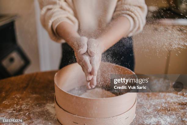 femme secouant la farine de ses mains - passoire photos et images de collection