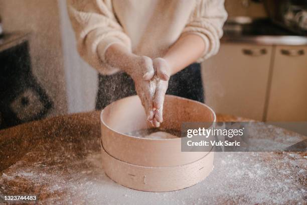 femme secouant la farine de ses mains - passoire photos et images de collection